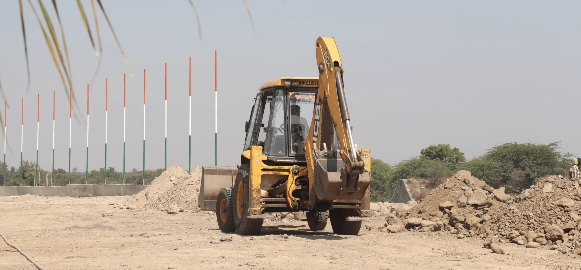 Backhoe loader working a graded dirt lot during site preparation